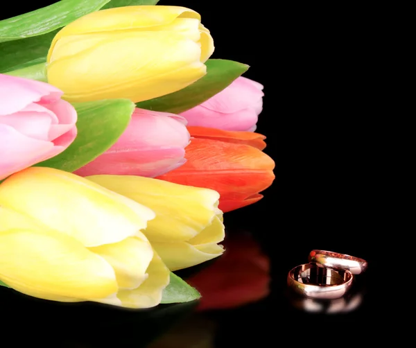 stock image Tulips and two gold rings on a black background