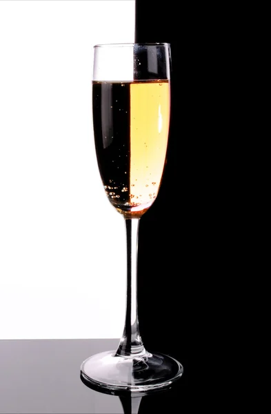 Glass with champagne on white and black background — Stock Photo, Image