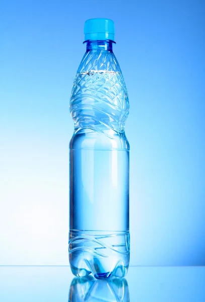 Láhve vody na modrém pozadí — Stock fotografie