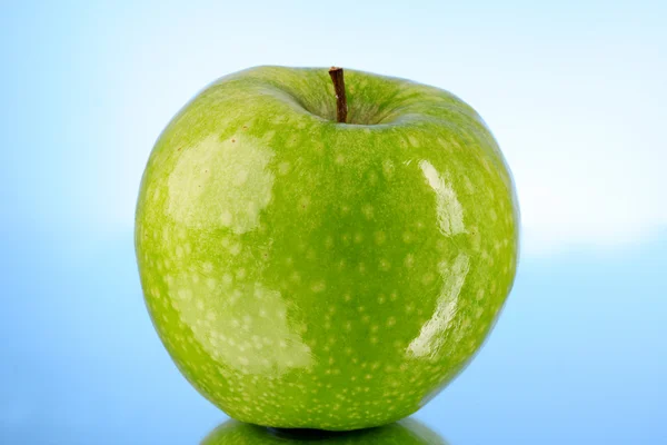 Green apple on blue background — Stock Photo, Image