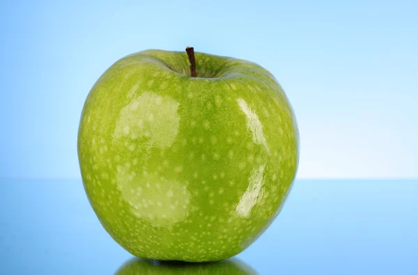Zielone jabłko na niebieskim tle — Zdjęcie stockowe