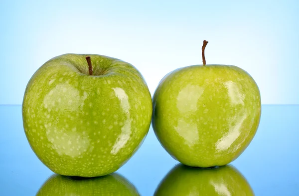 Zwei grüne Äpfel auf blauem Hintergrund — Stockfoto