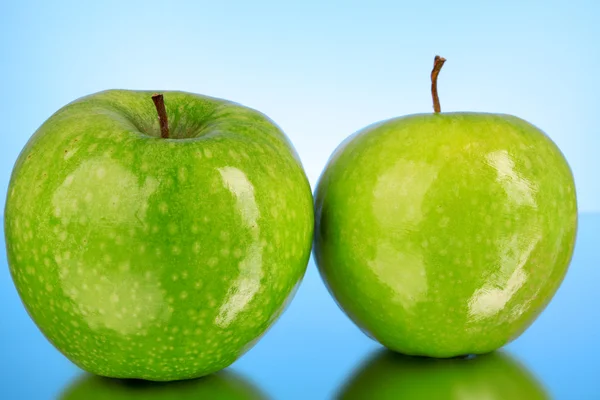 stock image Two green apples on blue background