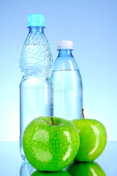 Flessen water op blauwe achtergrond — Stockfoto