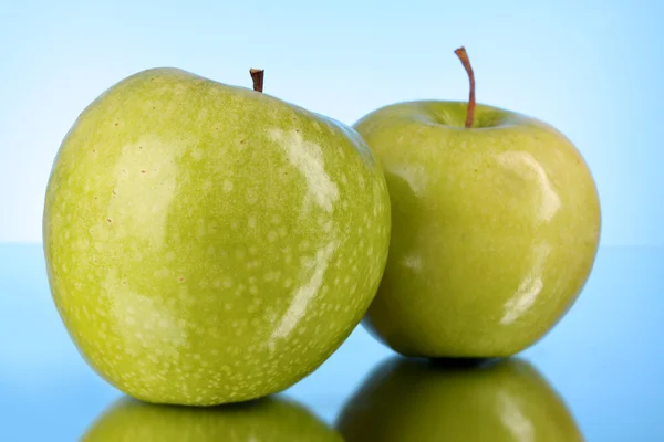 Dvě zelená jablka na modrém pozadí — Stock fotografie