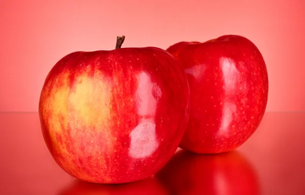 Kaksi punaista omenaa punaisella taustalla — kuvapankkivalokuva