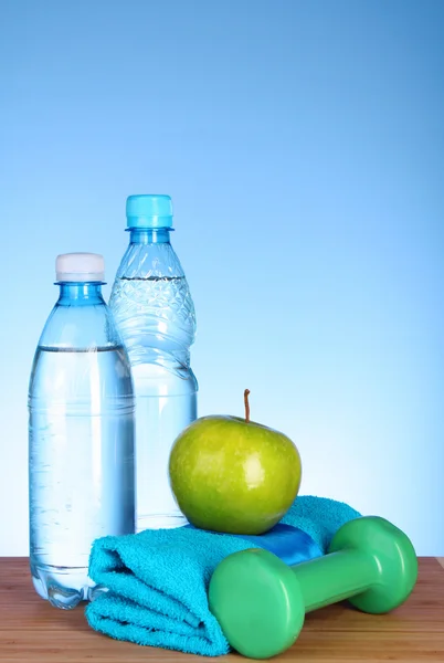Blue bottle of water, apple, sports towel,dumbbells and measure — Stock Photo, Image