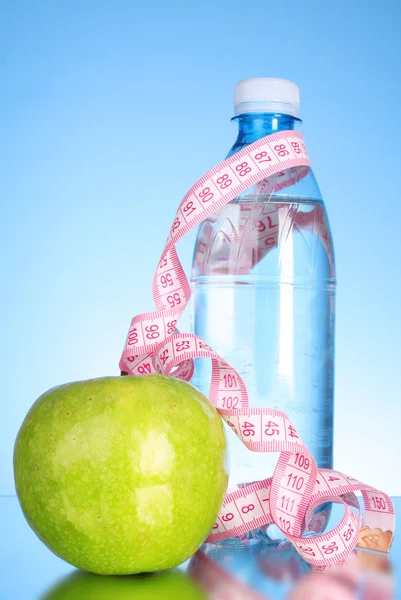 Fresh red tasty apple, bottle with measuring tape on blue backgr — Stock Photo, Image