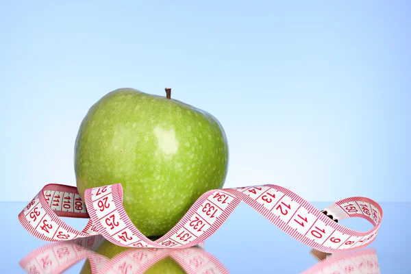 Fresco mela rossa gustosa con nastro di misurazione su sfondo blu — Foto Stock