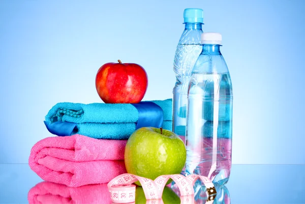Modrá láhev vody, jablko, sportovní ručník a měření pásky na bl — Stock fotografie