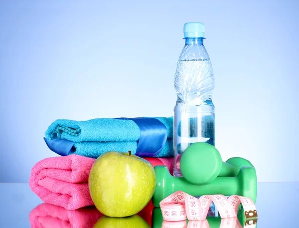 Bottiglia blu di acqua, mela, asciugamano sportivo, metro a nastro e muto — Foto Stock