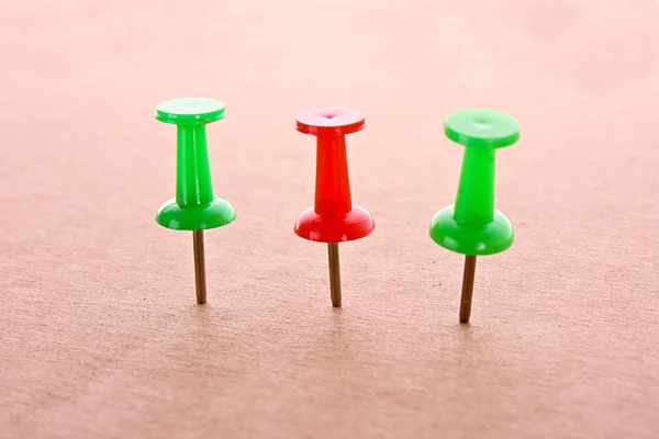 Three colourful pins on cardboard — Stock Photo, Image