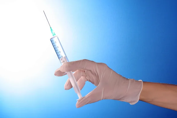 Syringe in doctors hand over blue background — Stock Photo, Image
