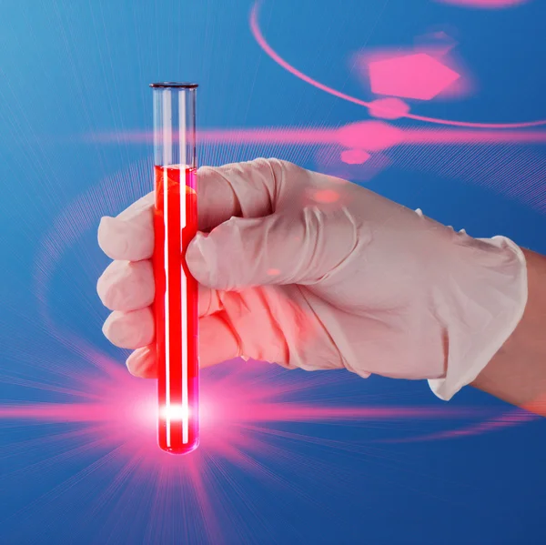 青色の背景に赤灯で手でテスト チューブ — ストック写真