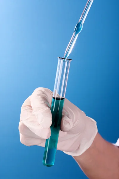Reagenzglas in der Hand über blauem Hintergrund — Stockfoto