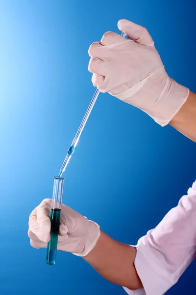 파란색 배경 위에 손에 테스트 튜브 — 스톡 사진