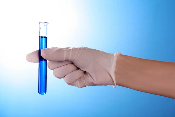 Reagenzglas in der Hand über blauem Hintergrund — Stockfoto