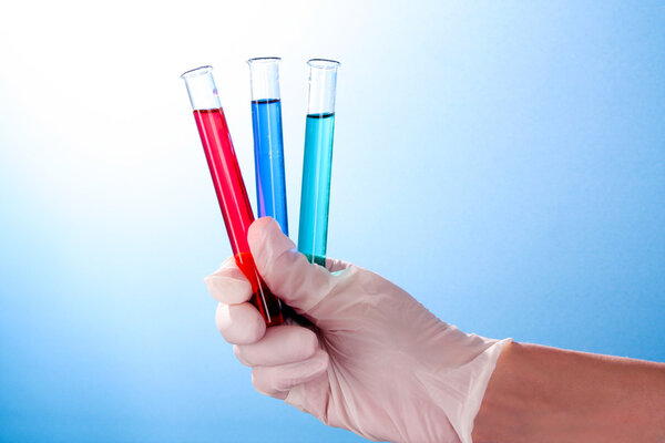 Test tube in hand over blue background