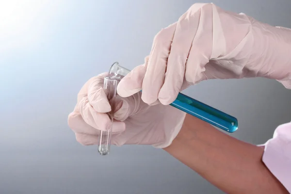 Someone pour test tubes on blue background — Stock Photo, Image