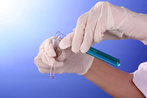 Tubos de teste de laboratório nas mãos do médico no backgrou azul — Fotografia de Stock
