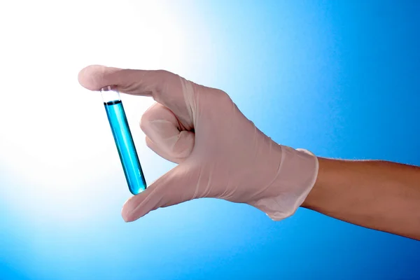 파란색 배경 위에 손에 테스트 튜브 — 스톡 사진