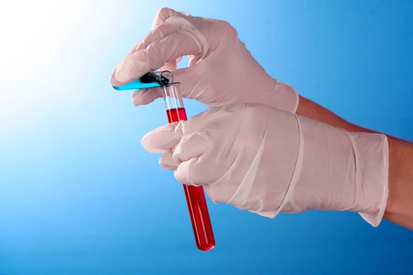Someone pour test tubes on blue background — Stock Photo, Image