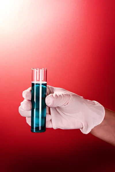 Reagenzglas in der Hand über rotem Hintergrund — Stockfoto