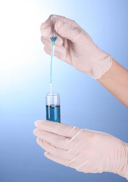 Equipamento de laboratório à mão sobre fundo azul — Fotografia de Stock