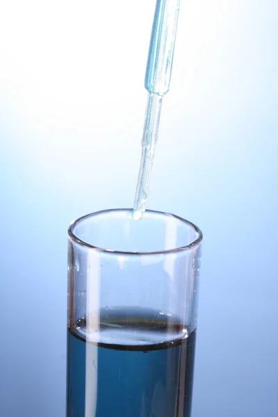 Nahaufnahme aus dem Reagenzglas auf blauem Hintergrund. Tropfen aus dem Teststock — Stockfoto
