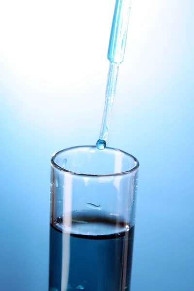 Nahaufnahme aus dem Reagenzglas auf blauem Hintergrund. Tropfen aus dem Teststock — Stockfoto