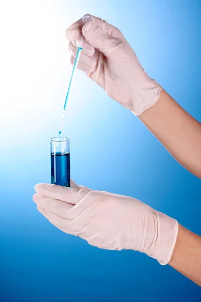 实验室设备在蓝色背景上的手 — 图库照片