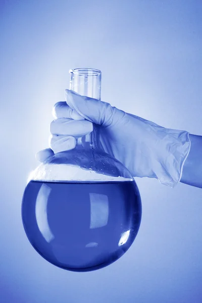 Flask in hand on blue background — Stock Photo, Image