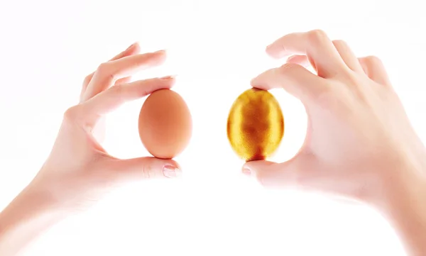 Gold and simple egg in hands isolated on white — Stock Photo, Image