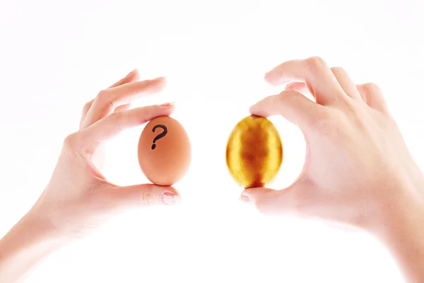 白で隔離される手で金とシンプルな卵 — ストック写真
