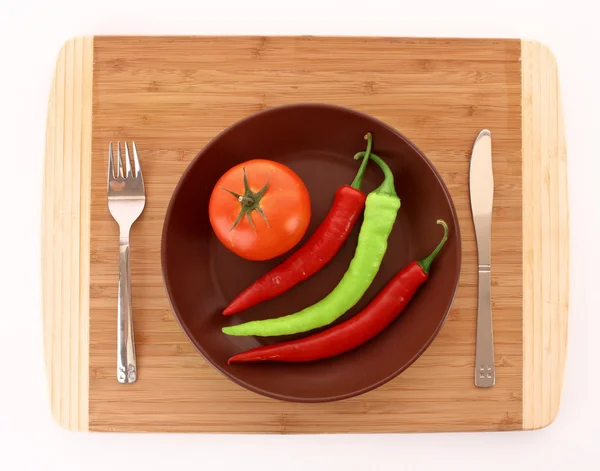 Тарілка з перцем, помідором, виделкою і ножем ізольована на білому — стокове фото