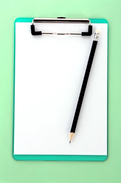 Clipboard e lápis sobre fundo verde — Fotografia de Stock