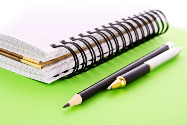 stock image Notepad, pencil and pen on green background