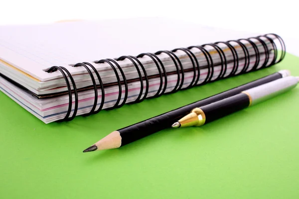 Kladblok, potlood en pen op groene achtergrond — Stockfoto