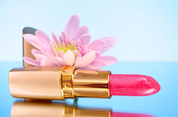 New lipstick and flower on blue background — Stock Photo, Image