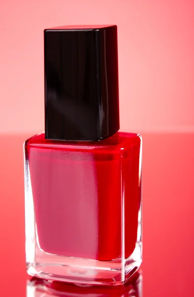 Esmalte de uñas rosa sobre fondo rojo — Foto de Stock