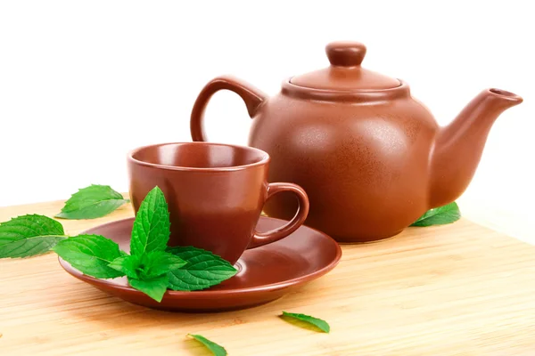Šálek zeleného čaje na talířku s mátou na dřevěné desce — Stock fotografie