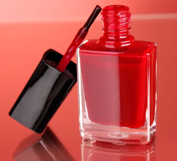 Różowy lakier do paznokci na czerwonym tle — Zdjęcie stockowe