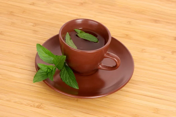 Cup of green tea on the saucer with mint on wooden surface — Stock Photo, Image