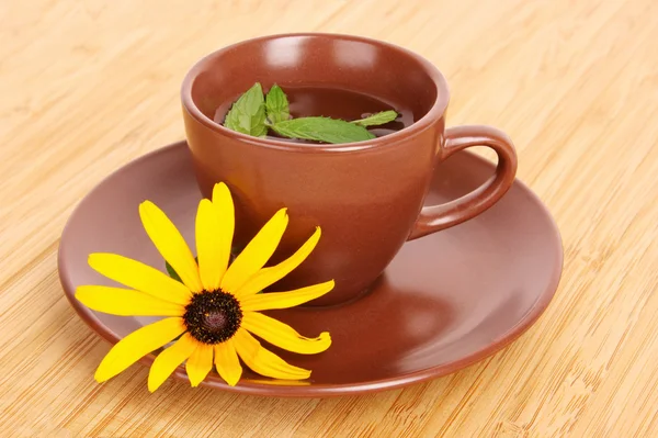 Cup of green tea on the saucer with yellow flower — Stock Photo, Image