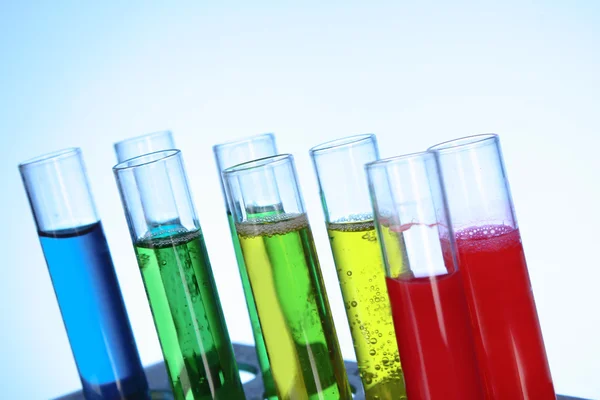 Multicoloured test tubes in the stand on blue background — Stock Photo, Image
