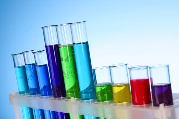 Multicoloured test tubes in the stand on blue background — Stock Photo, Image