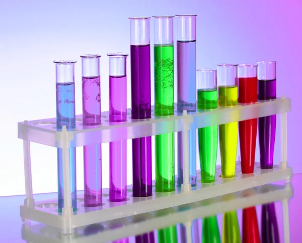 Multicoloured test tubes in the stand on purple background — Stock Photo, Image