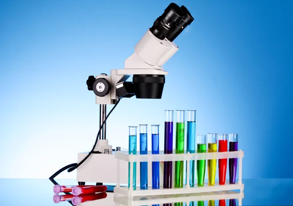Лабораторний металевий мікроскоп і пробірки з рідиною на синьому b — стокове фото