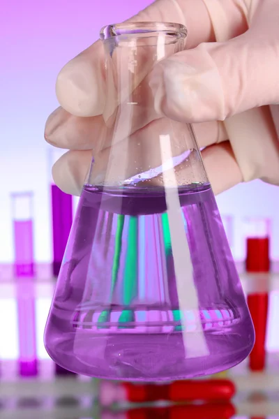 Коническая колба с фиолетовой жидкостью на фиолетовом фоне с тестом - — стоковое фото