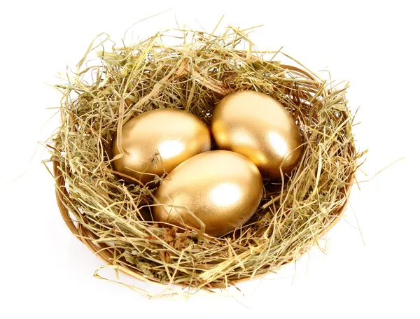 Tři zlaté vejce v travnaté hnízdo izolovaných na bílém — Stock fotografie